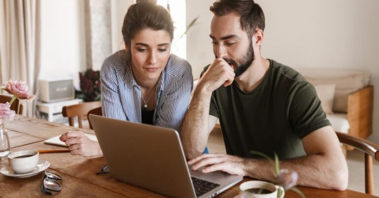 Couple reviewing information together on a laptop at home.